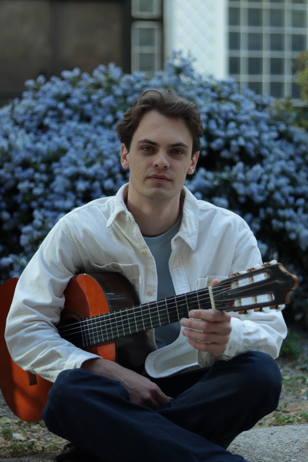 Baptiste Erard avec sa guitare devant un arrière-plan fleuri